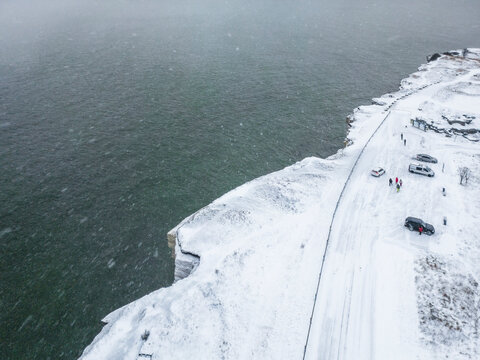 Aerial view of snowy Parki cliffs and the frozen Baltic Sea with a scenic road and cars, Paldiski, Harju, Estonia.