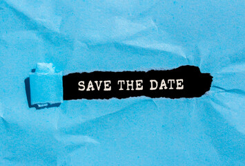 Save the date message written on ripped blue torn paper on black background. Conceptual save the date symbol. Copy space.