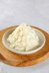 Shea butter in a plate on a light background. Vertical orientation.