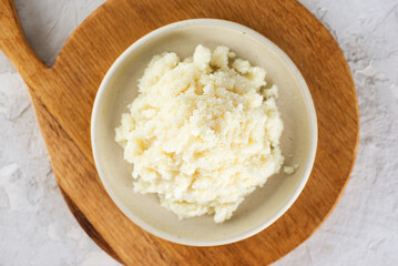 Edible shea butter in a plate on wooden board. Top view.