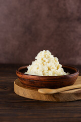 Unrefined raw shea butter in a clay bowl on a wooden table. Vertical orientation.