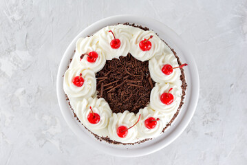 Vegan black forest cake, Schwarzwald pie on a gray table. Cake with dark chocolate, whipped cream and cherry. Top view.