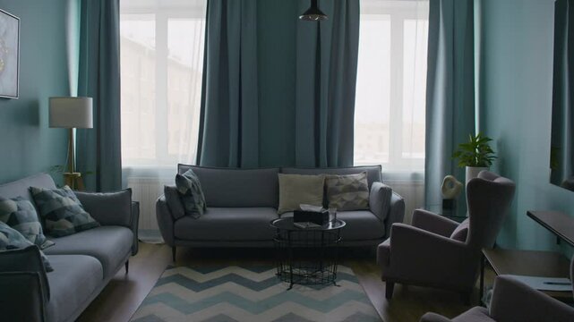 Interior of modern office of professional psychologist with grey sofas, armchair, small black table and turquoise curtains