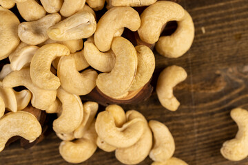 large cashew nuts are scattered on a larch board