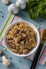 Pork with bulgur and champignons served in white bowl on blue table
