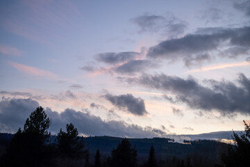 Dramatic unset sky with clouds and sunlight over hills