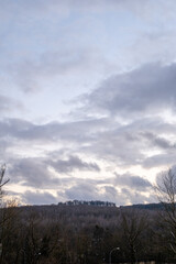 Dramatic unset sky with clouds and sunlight over hills