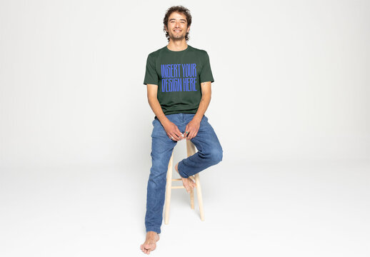 Mockup of Casual T-Shirt Design With Model Seated on Stool