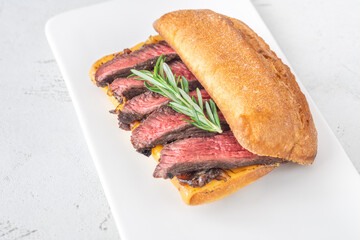 Grilled ciabatta sandwich with melted cheese, juicy steak, caramelized onions, and rosemary