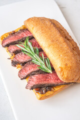 Grilled ciabatta sandwich with melted cheese, juicy steak, caramelized onions, and rosemary