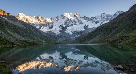 Fototapeta premium A peaceful alpine lake reflects majestic snow-capped mountains under clear blue skies. Great for adventure, serenity, and outdoor exploration visuals