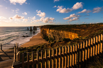 View from fenced lookout of coastal monoliths known as The Twelve Apostles, in beautiful the sunset
