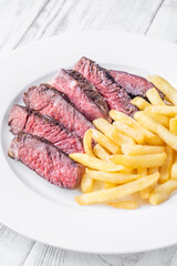 Sliced Medium-Rare Ribeye Steak with French Fries on White Plate