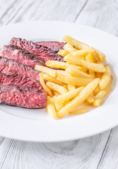 Sliced Medium-Rare Ribeye Steak with French Fries on White Plate