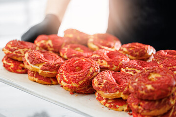 Freshly baked donuts with red topping in bakery factory setting