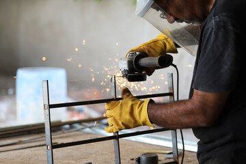 
Man in safety gear cutting metal fence with electric grinder