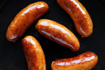 Fried pork sausages on black background, close-up view, top view