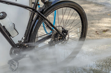 Washing bicycle at car wash with stream of water