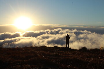 silhueta de homem caminhando em montanha com mar de nuvens ao fundo - foto tirada em santa catarina, na serra do rio do rastro