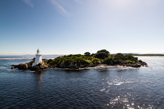 Small island with a cute little lighthouse, blue sky and bluewater.