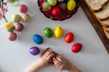 Beautiful blond child, boy, coloring and painting eggs for Easter at home