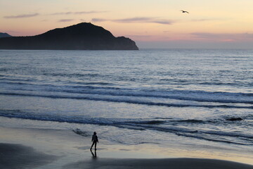 mulher caminhando na beira da praia no nascer do sol em garopaba, santa catarina