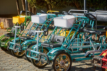 Fototapeta premium Rental mechanical quadricycle in the park. Four person tandem bicycle for rent