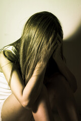 Sad woman sitting and crying at wall.