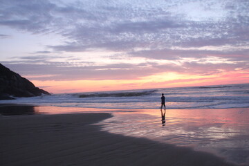 Fototapeta premium homem caminhando em praia no nascer do sol em florianópolis, santa catarina