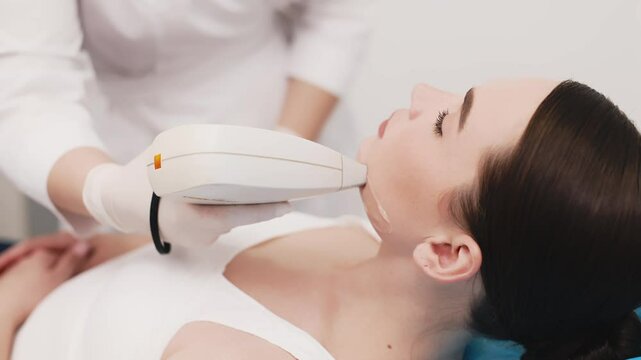 A beautiful woman undergoing a facial laser hair removal procedure in a beauty salon. Concept of professional and effective skincare treatments in a modern spa setting.