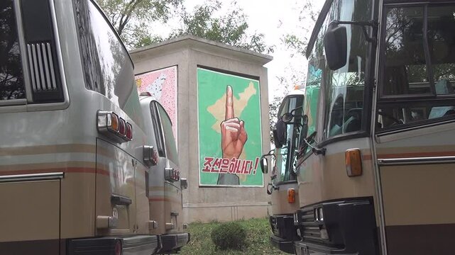 Buses for tourists near reunification poster on the DMZ, Panmunjom, North Korea