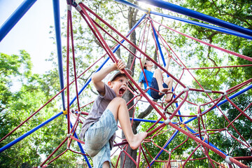 Young boy climbing spiderweb playground equipment at park