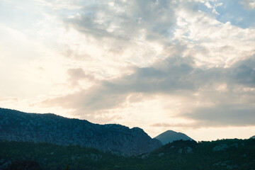 Mountain silhouettes under dramatic sunset clouds. Serene dusk landscape with soft light