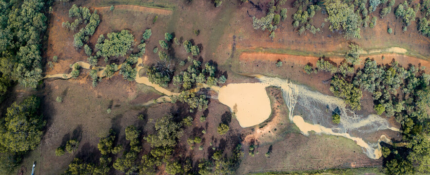 Full creek and overflowing dam in rural paddock