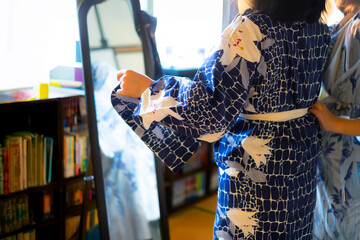 浴衣の着付けをしてもらう女性