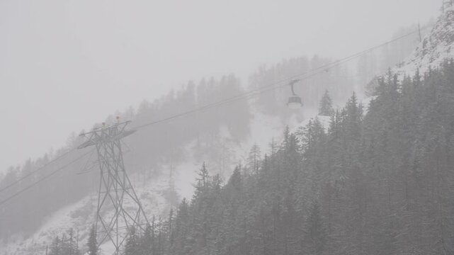View of Skyway Monte Bianco Cable Car returning to station with snow falling, Courmayeur, Aosta Valley, Italian Alps, Italy