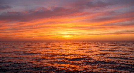 A stunning sunset over the ocean, with warm orange and pink hues reflecting on the water.