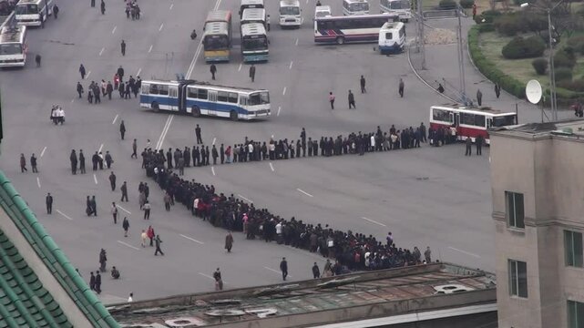 Crowd of North Korean people queueing in line for a bus, Pyongyang, North Korea