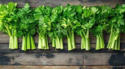 Fresh green celery stalks arranged neatly on a rustic wooden surface