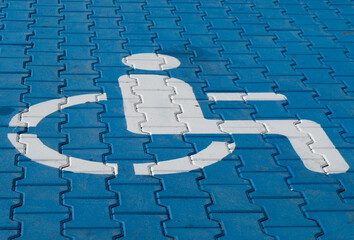 A blue pavement features a white accessibility symbol, highlighting a space designed to support...