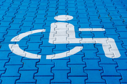 A designated blue parking spot features a prominent white accessibility symbol, signaling its use for individuals with disabilities in a busy area
