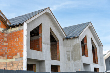 Workers are engaged in construction, focusing on residential buildings with brick walls and missing windows under an expansive blue sky