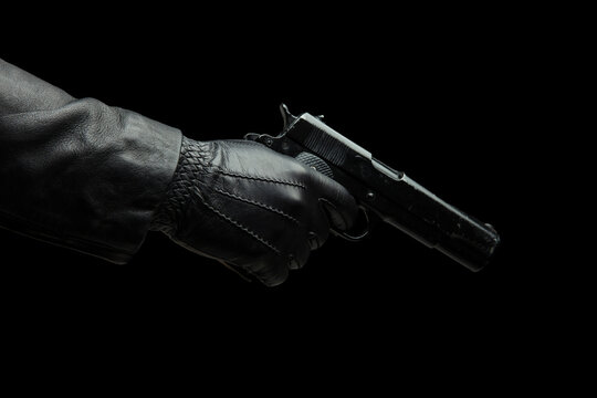 Gun on dark background, closeup, gloved hand holding a pistol. Crime, murder