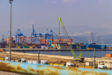 Turkiye, Izmir - March 1, 2024: Aerial view of Port of Liman filled with vibrant cargo containers, cranes, and busy dock operations under a clear blue sky.
