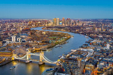 The vibrant evening sky casts a golden glow over Tower Bridge as it spans the River Thames,...