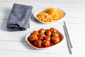 Crispy vegetable Manchurian balls tossed in spicy, tangy sauce, served with flavorful stir-fried noodles for a delicious Indo-Chinese meal.