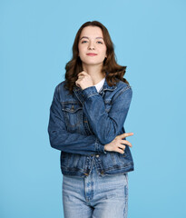Portrait of a pretty girl with a slight smile, white T-shirt and denim jacket looking at the camera, isolated on blue background.