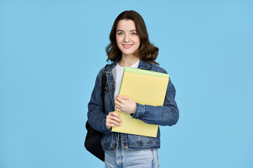 Pretty student girl holding notebooks and looking at camera, isolated on blue background.