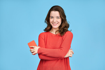 Portrait of young happy woman isolated on blue background, holding phone and looking at camera.