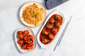 Crispy vegetable Manchurian balls in spicy, tangy sauce, served with stir-fried noodles and crunchy Gobi Manchurian for a flavorful Indo-Chinese feast.